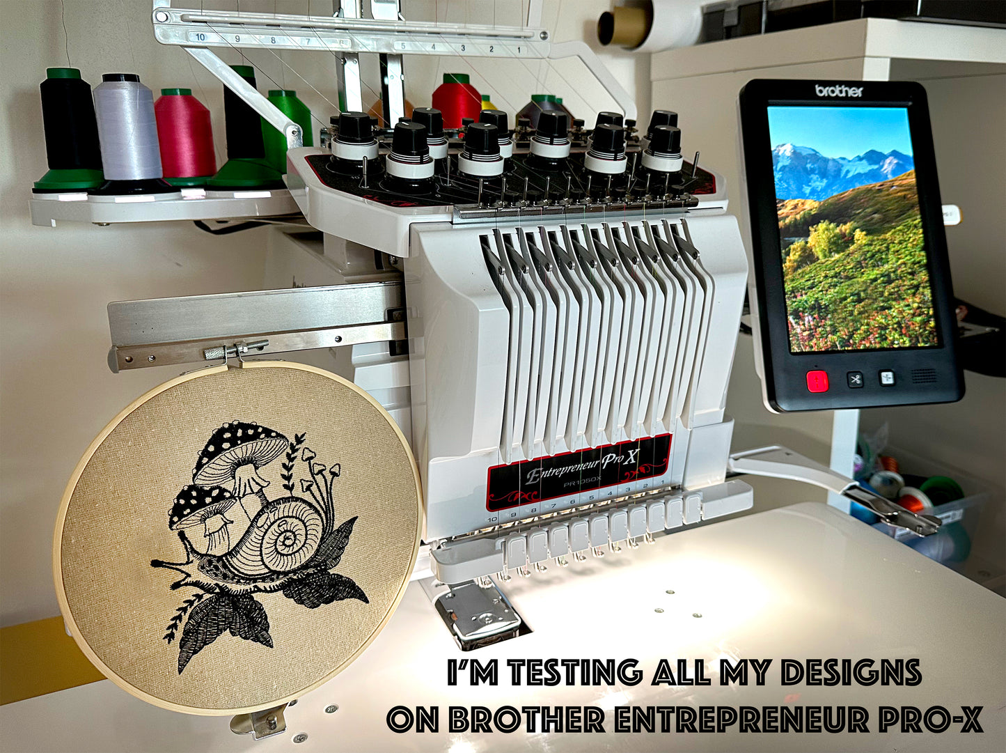 Embroidery machine with a screen displaying a mountain landscape and an embroidery hoop with a design.
