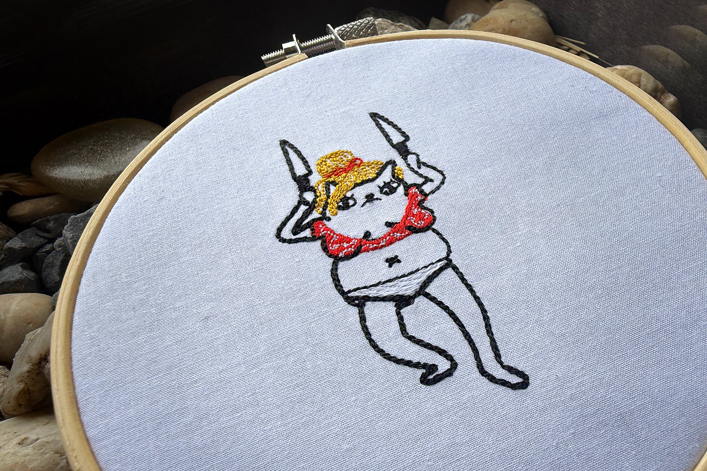 Cute minimalist embroidery design of a cat dressed as Britney Spears dancing with knives