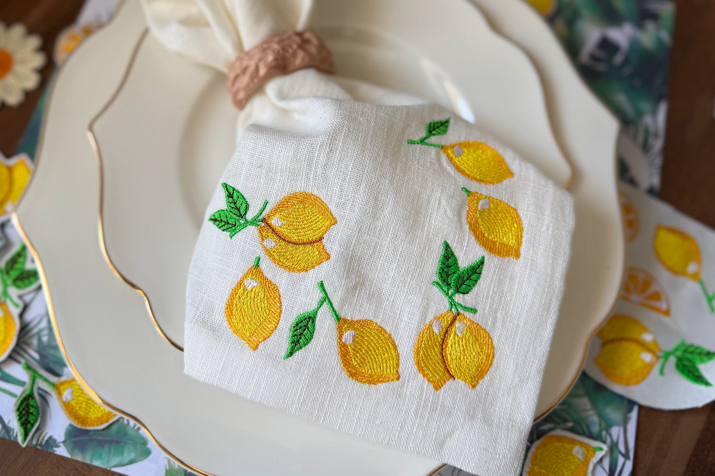Set of five embroidered lemon designs displayed on white fabric
