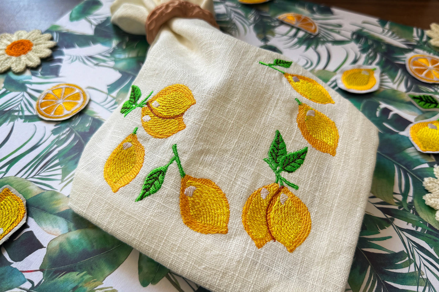 Embroidered towel with lemon designs on a decorative tablecloth.