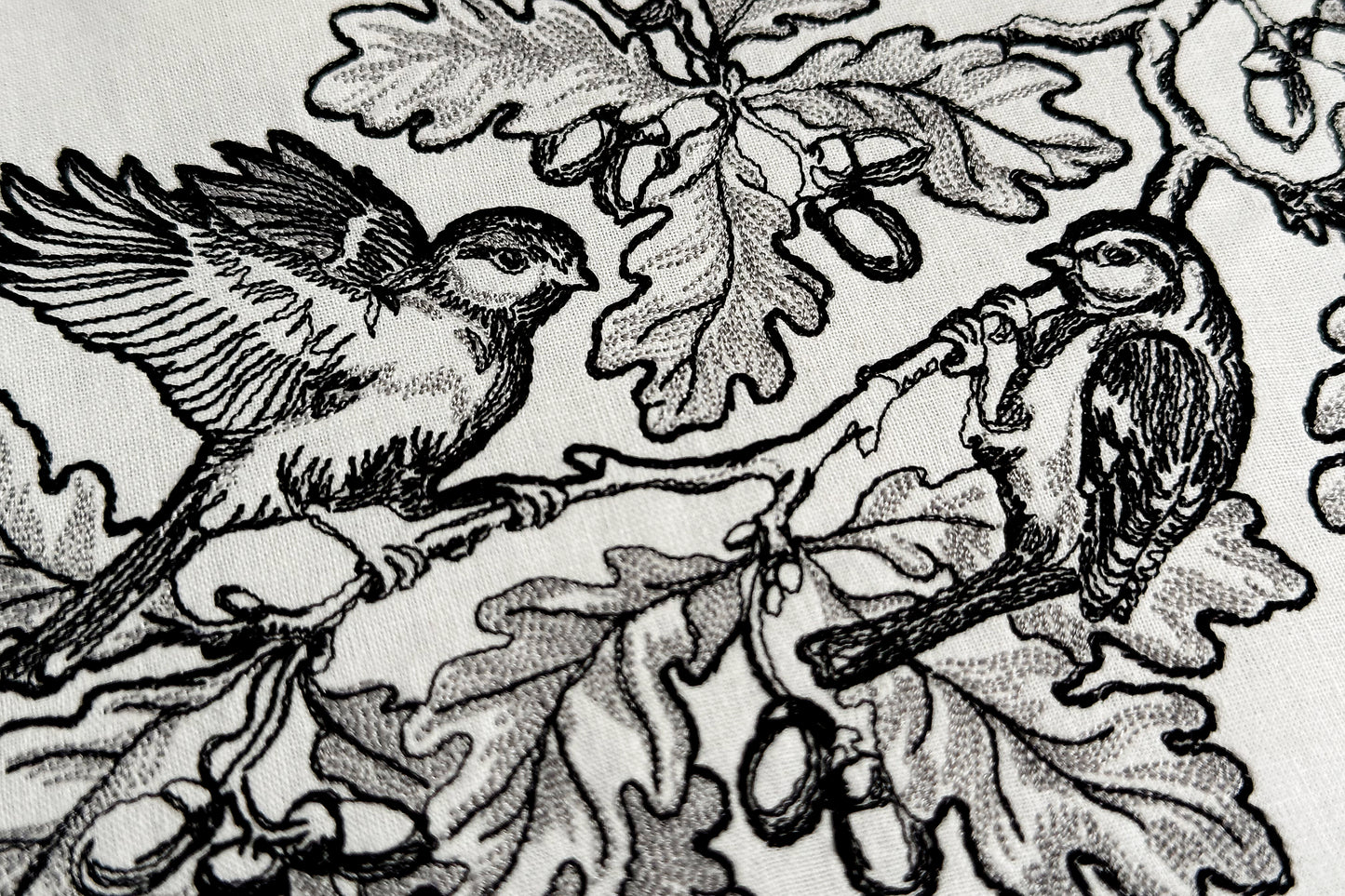 Decorative embroidery frame with oak leaves, acorns, and two birds