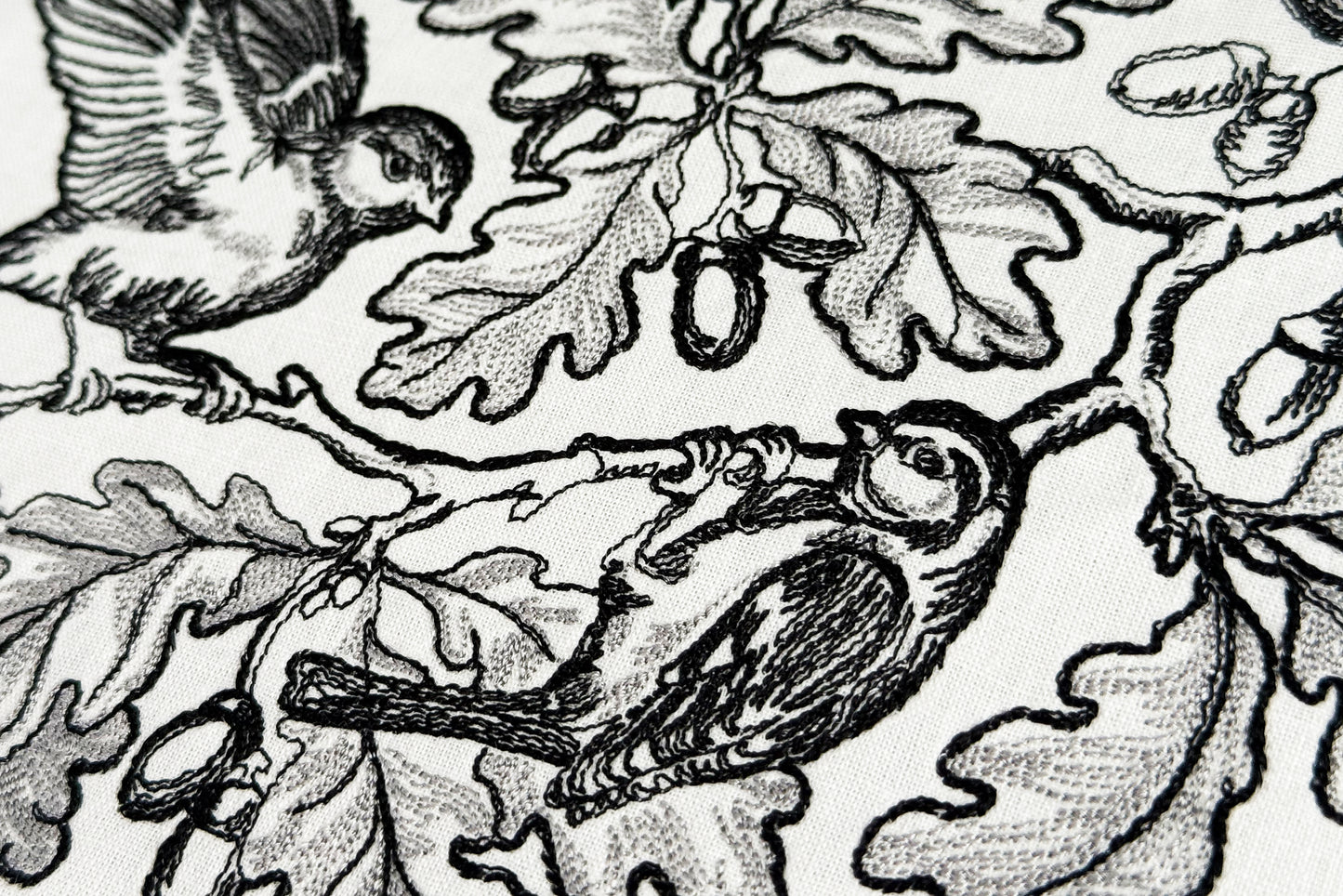 Detailed oak branch embroidery with flying bird and perched bird