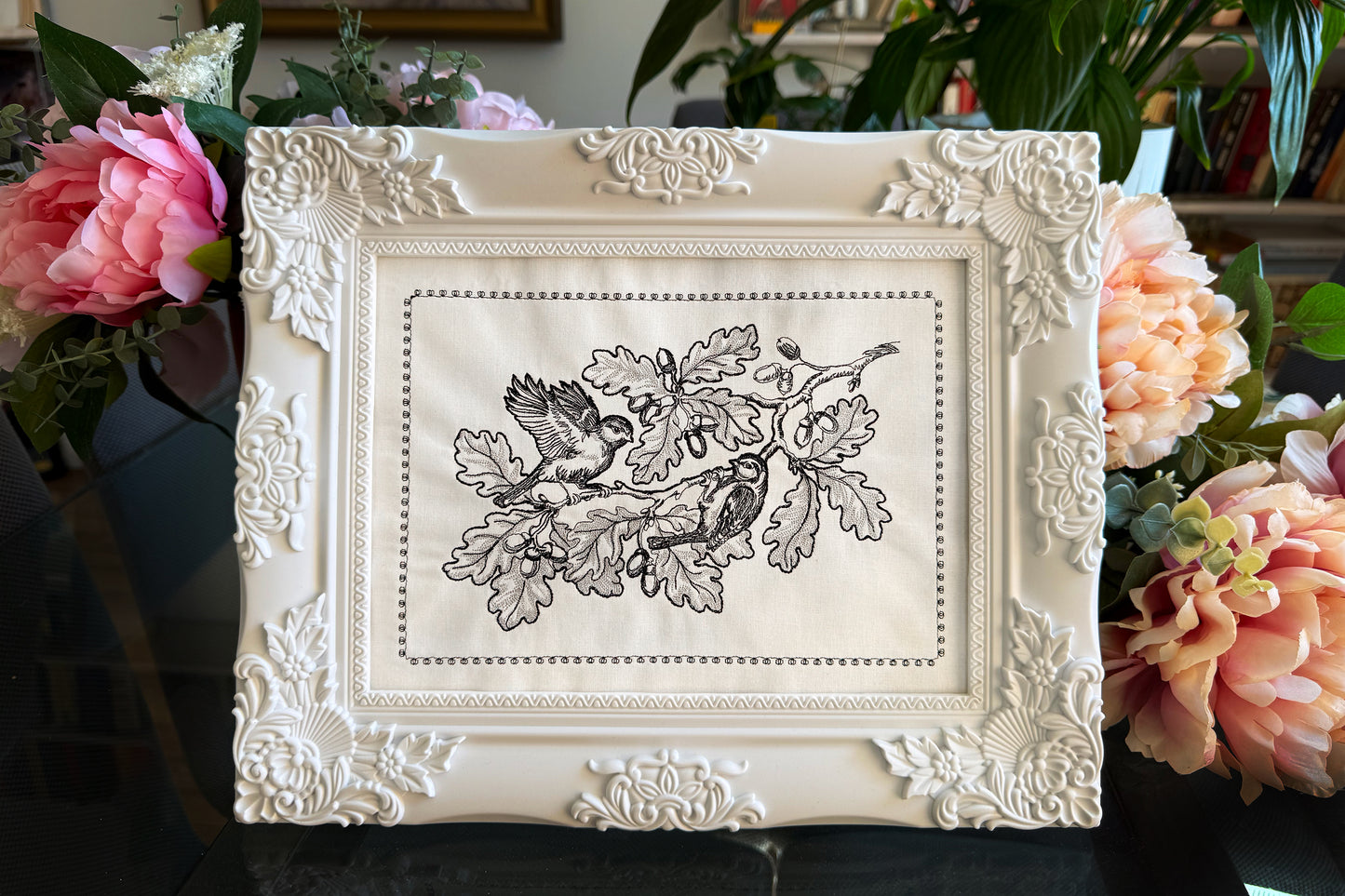Machine embroidery design of two birds on an oak branch with acorns