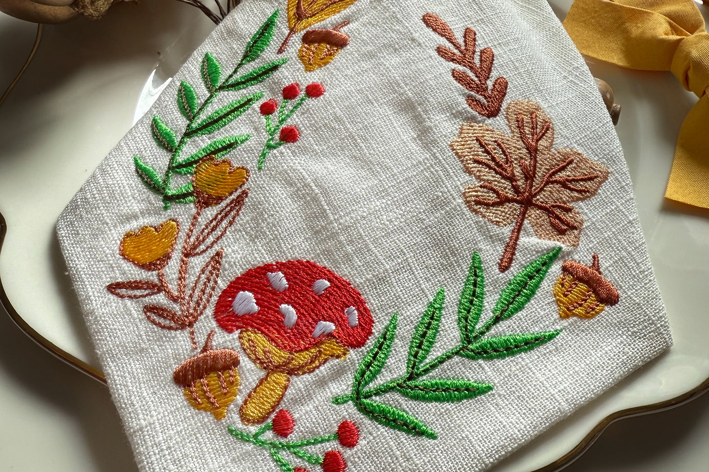 Embroidered towel with autumn-themed design on a white surface