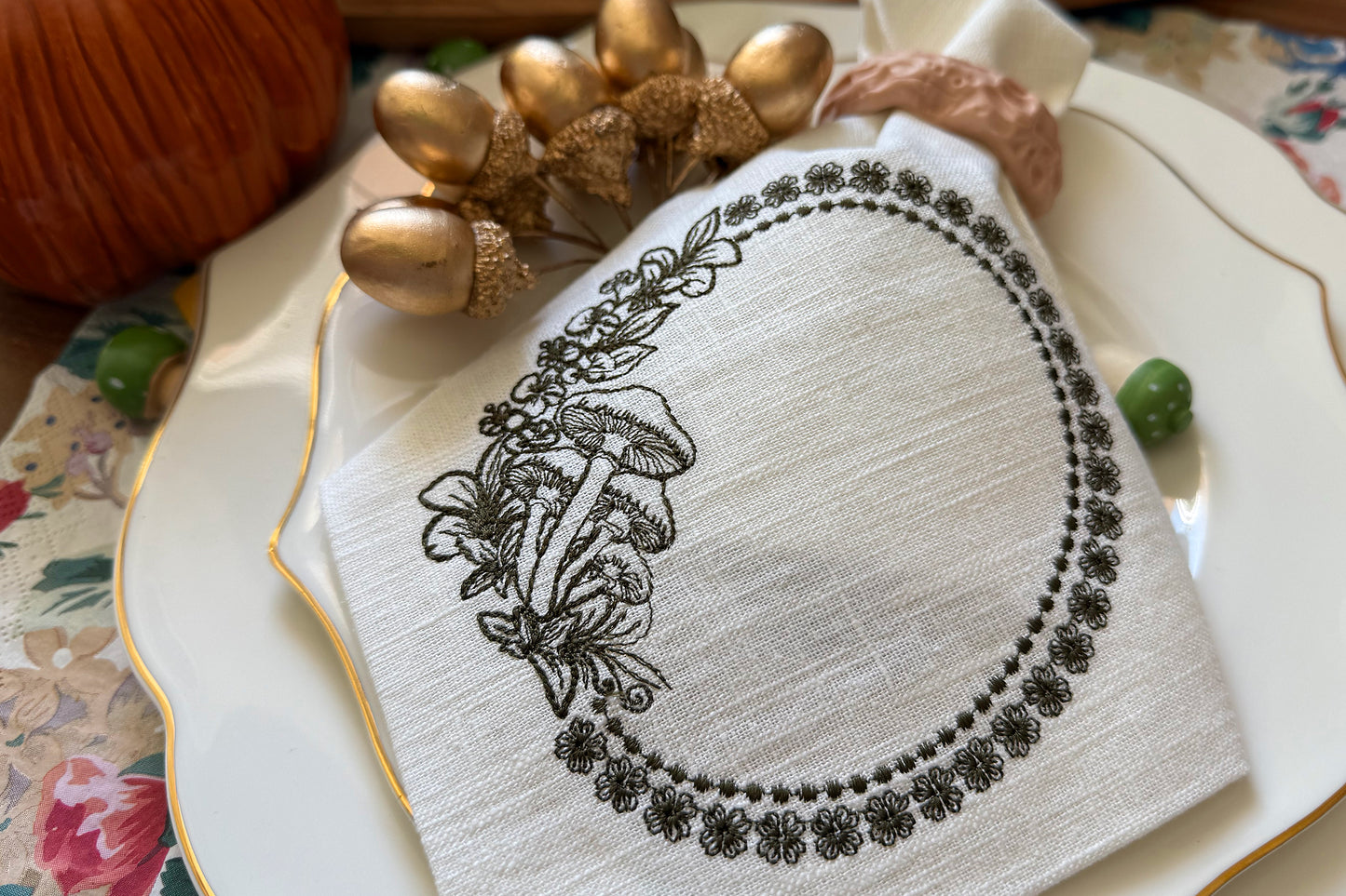 Decorative napkin with black floral design on a white plate with gold accents.