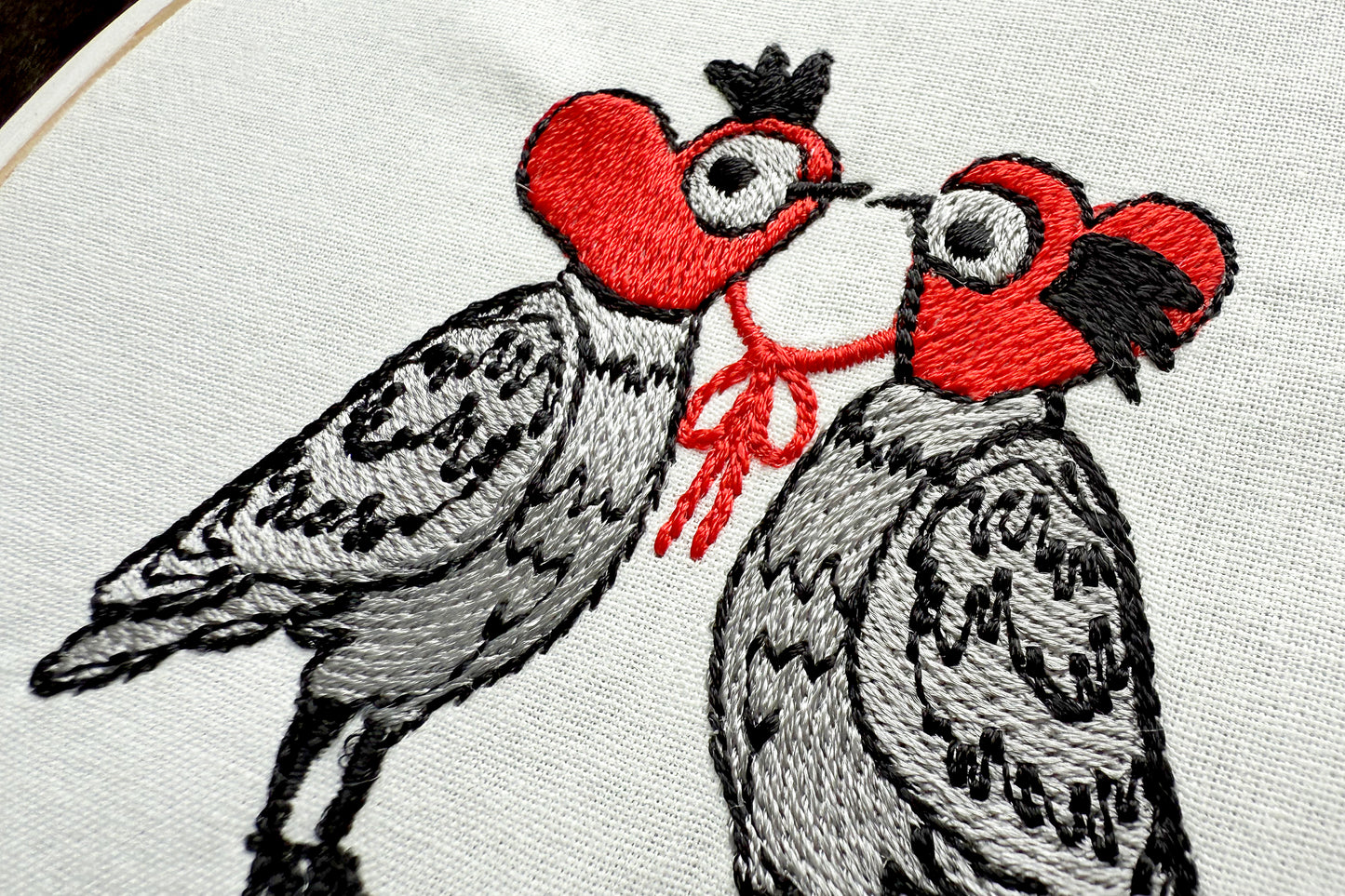 Cartoon-style doves in knitted heart hats machine embroidery