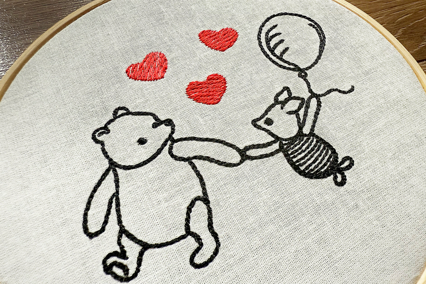 Close-up of Winnie and Piglet machine embroidery with hearts in red