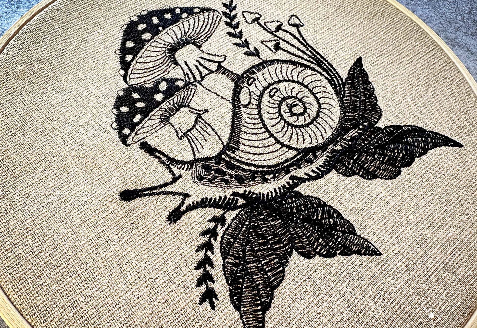 Forest-inspired line art embroidery hoop featuring a whimsical snail