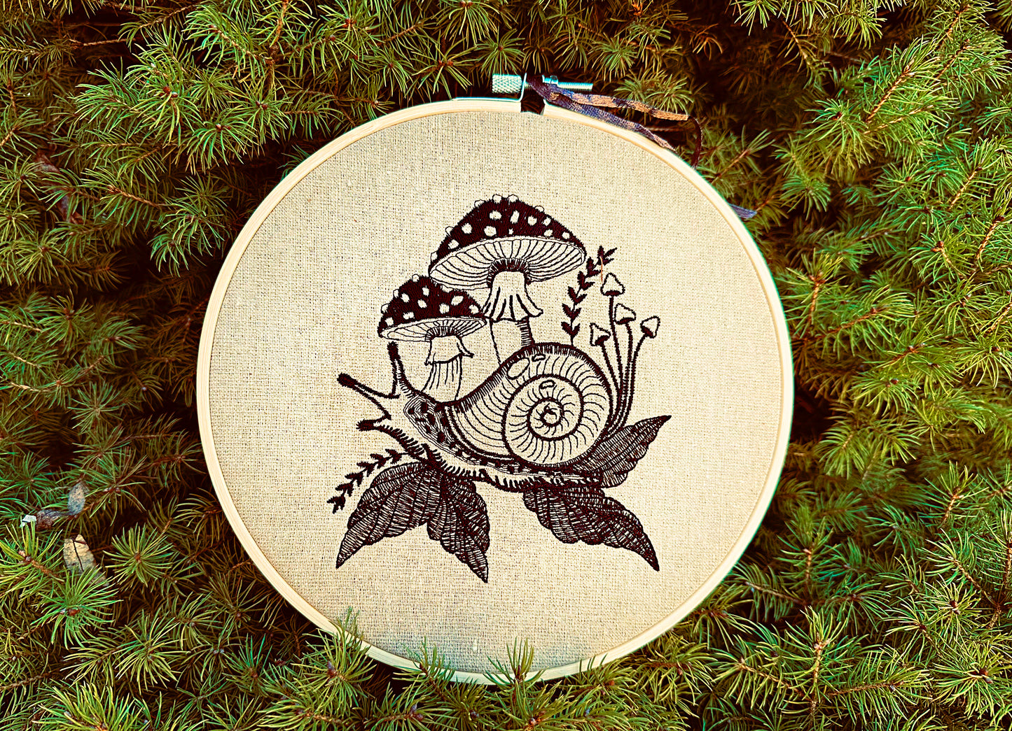 Blackwork snail embroidery with mushrooms and leaves on natural fabric