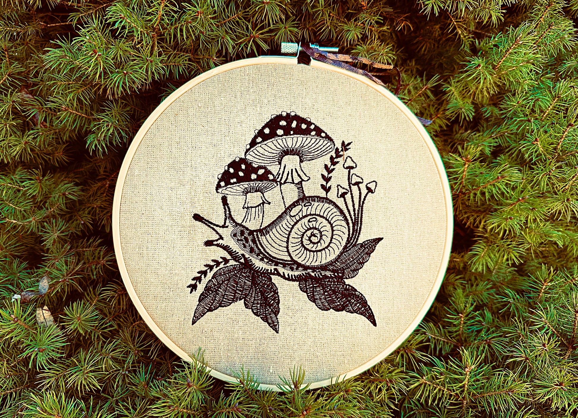 Blackwork snail embroidery with mushrooms and leaves on natural fabric