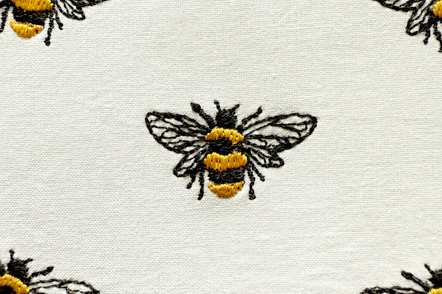 Realistic machine embroidery of a single bee on white fabric