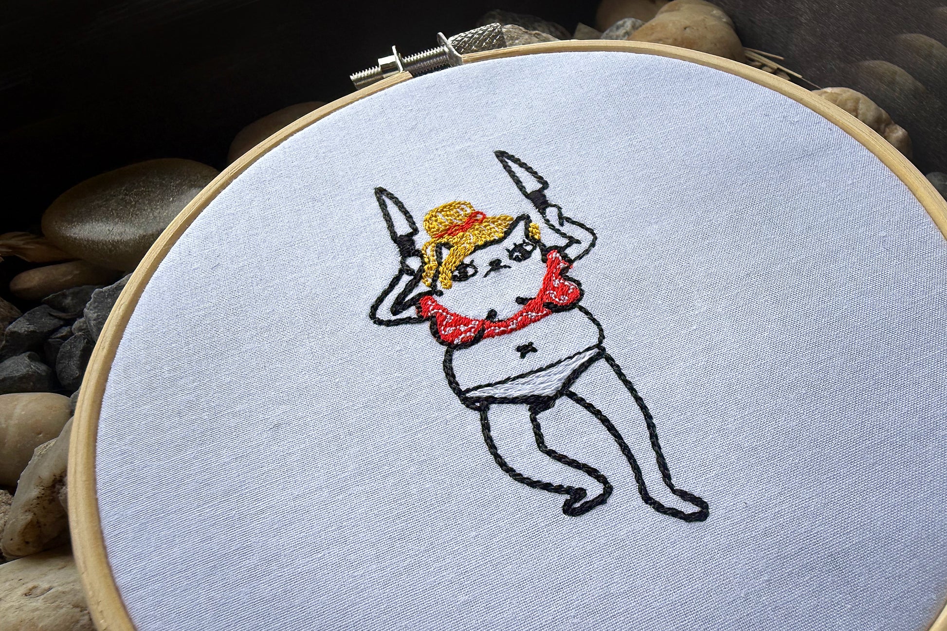 Cute minimalist embroidery design of a cat dressed as Britney Spears dancing with knives