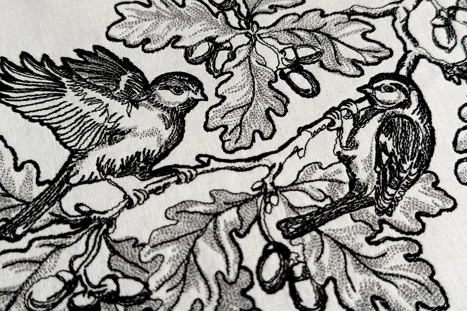 Decorative embroidery frame with oak leaves, acorns, and two birds