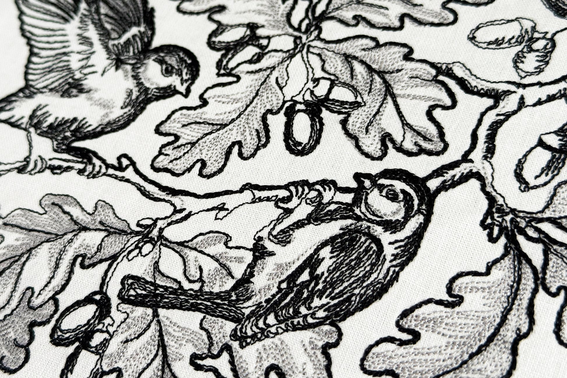 Detailed oak branch embroidery with flying bird and perched bird