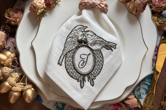Two birds sitting on an oval embroidery frame with hearts