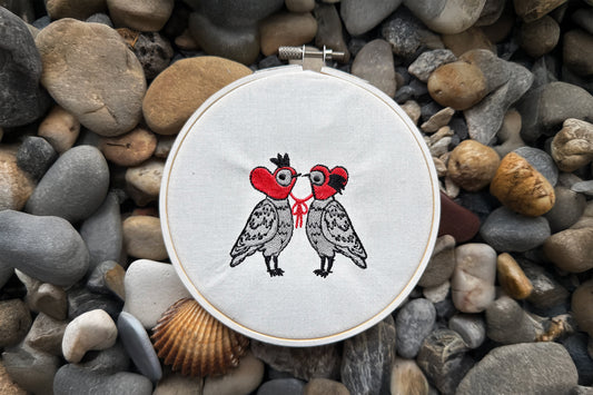 Machine embroidery design of two doves with heart hats and bow