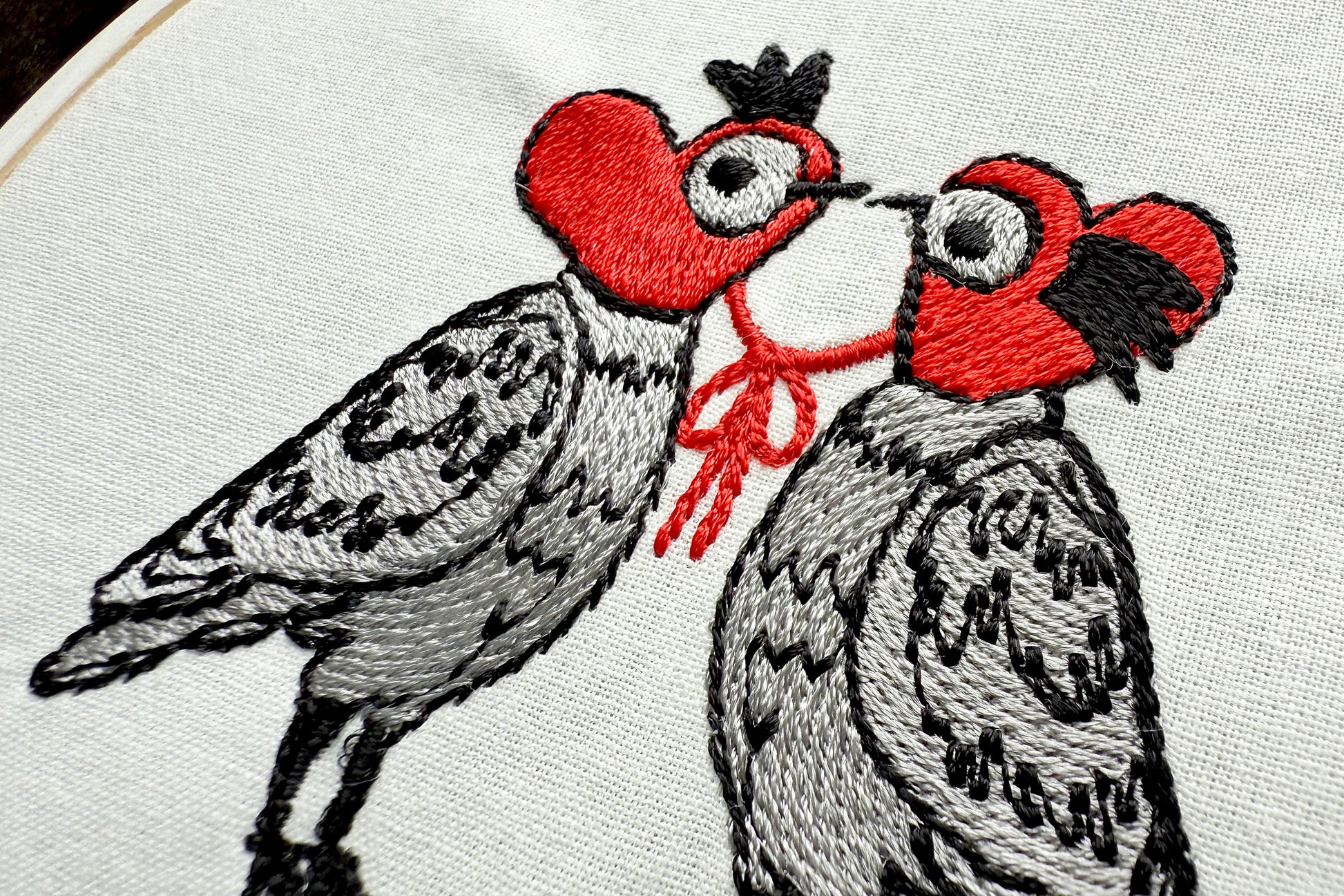 Cartoon-style doves in knitted heart hats machine embroidery