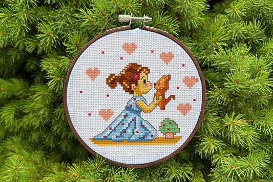 Cross stitch pattern of a girl in a blue dress holding a kitten with hearts