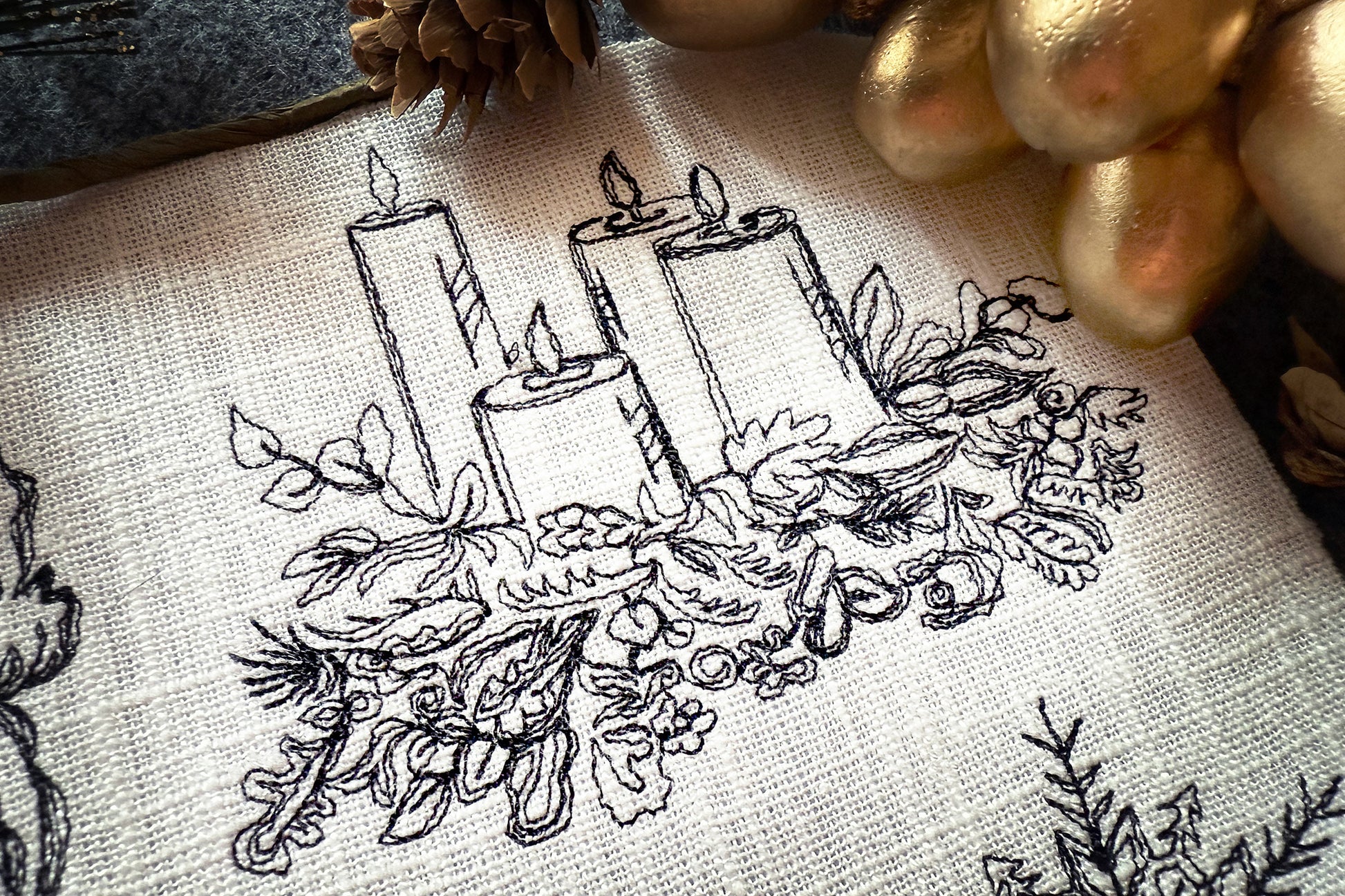 Embroidery design of candles and foliage on fabric with gold accents.