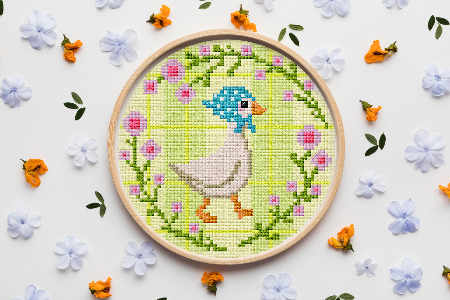 Cute goose cross-stitch pattern in blue headscarf with floral frame