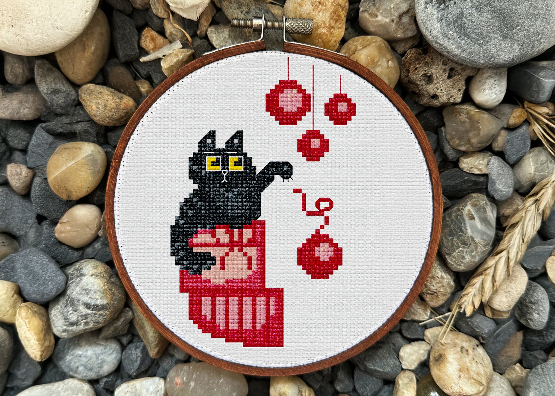 Minimalist black cat cross-stitch art with red baubles